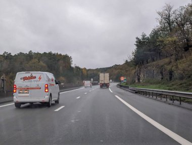 Fransa, 19 Kasım 2024: Orman manzaralı yoldan geçen araçlı yağmurlu otoyol