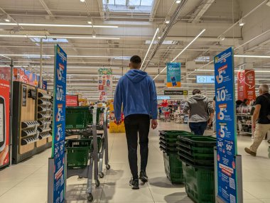 Fransa, 21 Eylül 2024: Mavi kapüşonlu adam bakkal koridorunda yürüyor.