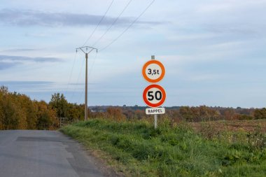Fransa, 27 Kasım 2024: Ağırlık ve hız sınırı işaretli kırsal yol sahnesi.