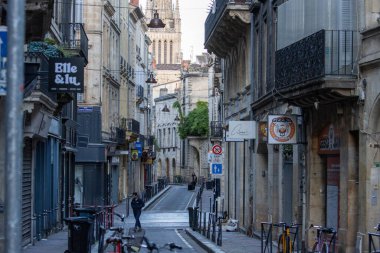 Fransa, Bordeaux, 05 Ekim 2024: Dükkanları ve uzak kilise kulesi olan Dar kaldırım taşı caddesi