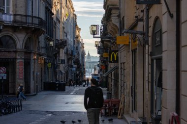 Fransa, Bordeaux, 05 Ekim 2024: Uzaktaki çeşmeye doğru yürüyen insanlarla dar Avrupa caddesi