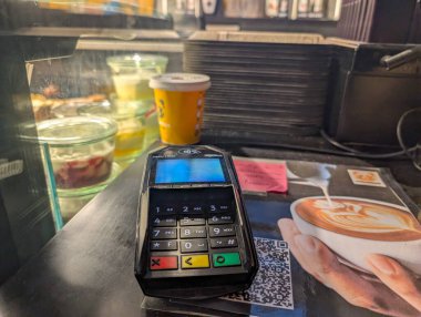 Fransa, 29 Kasım 2024: Ücret terminali ve tatlı sergisi hareketli bir kahve dükkanında.