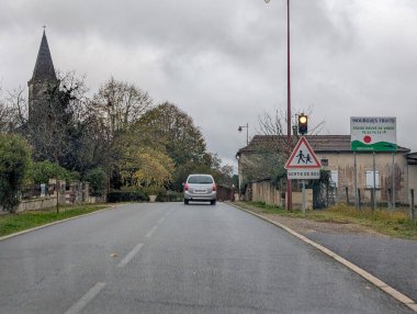 Fransa, 19 Kasım 2024: Okul otobüsü geçişi bulutlu kırsal yol manzarası