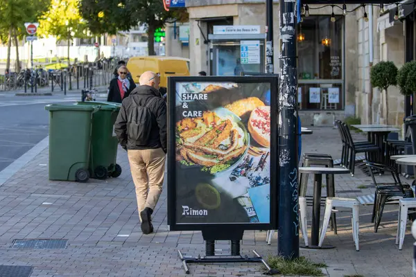 Fransa, Bordeaux, 05 Ekim 2024: Reklamlı sokak sahnesi ve şehir merkezinde yürüyen insan.