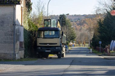 Fransa, 27 Kasım 2024: Kırsal yol kenarına park etmiş bir kamyon sonbahar yeşilliği arka planında
