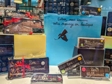 Fransa, 9 Ağustos 2024: Bir butik vitrininde kişisel mesajlarla sergilenen çikolatalar ve hediye kutuları