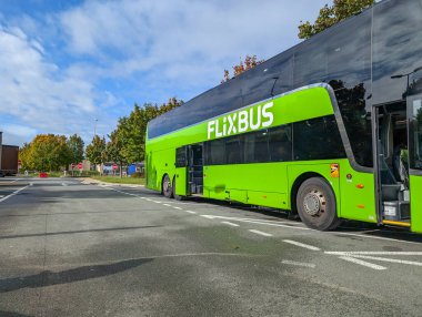Fransa, Bordeaux, 06 Ekim 2024: Yeşil çift katlı Flixbus ağaçlarla kaplı güneşli yolda park edildi.