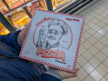 France, 07 December 2024 : Person holding pizza box in frozen food aisle store