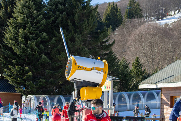 France, 01 January 2025 : Snow machine operating at ski resort with people enjoying activities