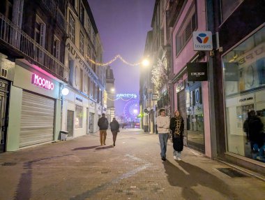 France, 31 December 2024 : Street scene with people and illuminated ferris wheel, night atmosphere clipart