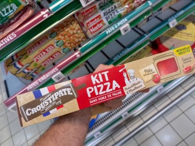 Fransa, 23 Aralık 2024: Süpermarket koridorunda elinde pizza seti kutusu var