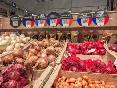 Fransa, 21 Aralık 2024: Markette soğan çeşitliliği sergilenirken fiyat etiketleri görülebilir