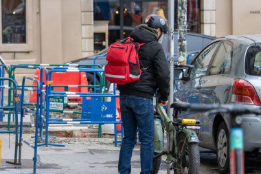 Fransa, Lyon 04 Şubat 2025: İnşaat alanı yakınında kırmızı sırt çantalı bir bisikletçi