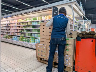 Fransa, 12 Aralık 2024: İşçi yoğun süpermarket koridorlarında süt ürünlerini stokluyor