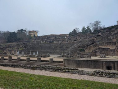 Fransa, Lyon 04 Şubat 2025: Yıpranmış kalıntıları, ağaçları ve yakınlarındaki binaları olan antik taş amfi tiyatro.