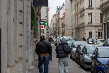 Fransa, Lyon 04 Şubat 2025: Dar yolda yürüyen insanlar, yakınlarda park etmiş arabalar.