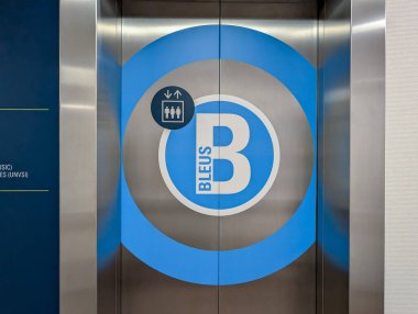 Fransa, 05 Mart 2025: Mavi daire logosu ve yön işareti olan asansör kapıları.