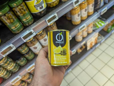 Fransa, 05 Mart 2025: Bir marketin koridorunda konserve zeytin tutan kişi