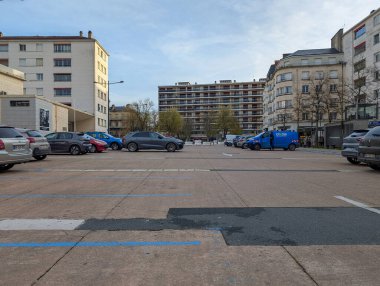 Fransa, 04 Nisan 2025: Çevresindeki binalar ve park edilmiş araçlarla açık otopark