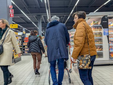 Fransa, 28 Mart 2025: Süpermarket müşterileri alışveriş arabalarıyla koridorlarda yürüyorlar