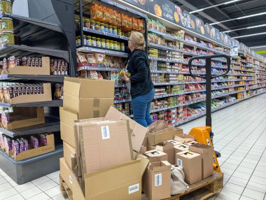 Fransa, 11 Nisan 2025: Süpermarket raflarında ürünleri düzenleyen işçiler ve kutular istiflendi.