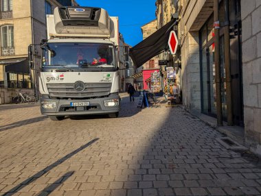 Fransa, 10 Nisan 2025: Fransız köyünde dar kaldırım taşı caddesinde seyir halindeki teslimat kamyonu.