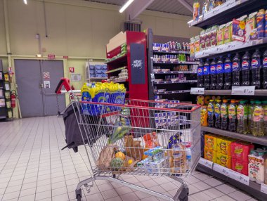 Fransa, 06 Mayıs 2025: Renkli süpermarket koridorlarında gıda dolu market alışveriş arabası