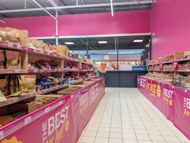 Fransa, 03 Mayıs 2025: Pembe süpermarket koridoru aperatiflerle dolu, güzellik salonu girişi görünür.