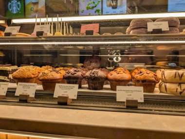 Fransa, 13 Mayıs 2025: Kahve dükkanında cam tezgahın arkasında çeşitli muffin ve tatlılar sergilendi