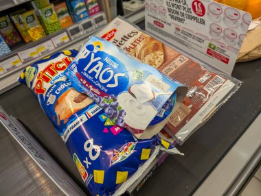 Fransa, 26 Nisan 2025: Abur cubur yoğurt suyu ve tanıtım vitriniyle market kasası