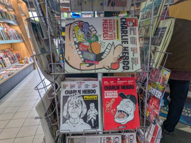 Fransa, 12 Nisan 2025: Bir mağaza ortamında Charlie Hebdo kapakları sergilenen dergi rafı.