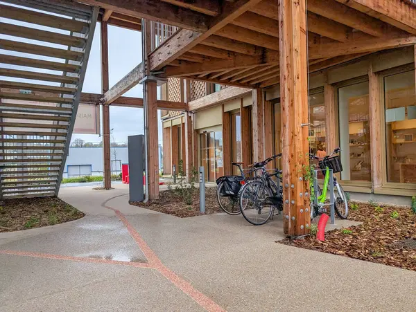 Fransa, 02 Nisan 2025: Bisikletler Ahşap Yapı Altında Modern Binalar Girişine Yakın Park Edildi