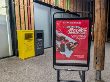 Fransa, 13 Mayıs 2025: Ahşap bir modern binanın içinde geri dönüşüm kutularıyla Coca Cola reklamı