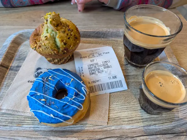 Fransa, 04 Nisan 2025: Ahşap masada renkli hamur işleri ve kahve makbuzu.