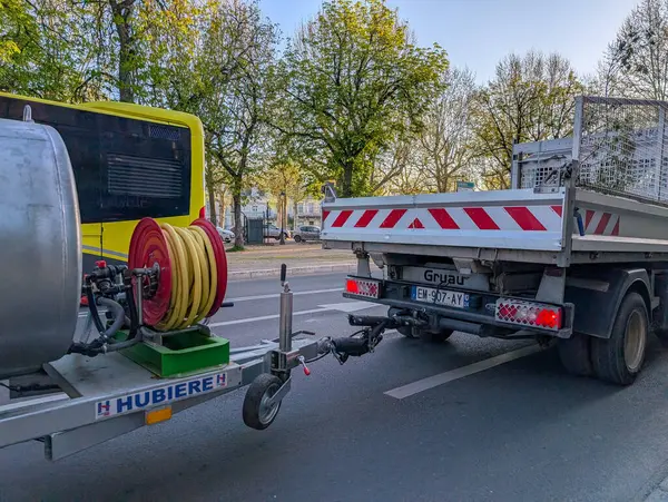 Fransa, 10 Nisan 2025: Şehir caddesinde ağaçlarla bağlantılı römork ve kamyon