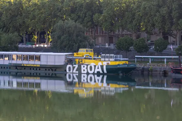 Fransa, 13 Mayıs 2025: Avustralya temalı yüzen bar Oz Boat nehir kenarındaki ağaçlarla kenetlendi