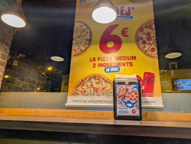 Fransa, 08 Mart 2025: Orta boy pizza reklamı, iki malzeme, restoran dekorasyonu.