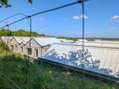 Fransa, 25 Nisan 2025: Açık yaz gününde tel örgülerin arkasındaki sanayi çatıları