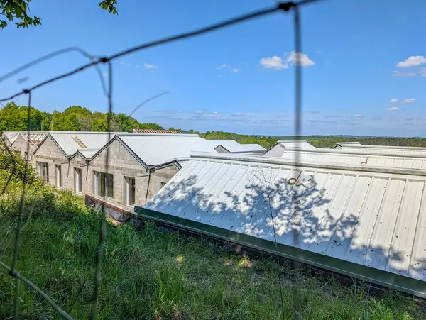 Fransa, 25 Nisan 2025: Açık yaz gününde tel örgülerin arkasındaki sanayi çatıları