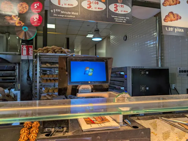 Fransa, 02 Mayıs 2025: Pasta tezgahı, menü tabelaları, yazar kasa ve bilgisayar.