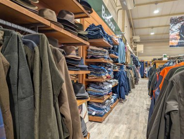 Fransa, 13 Mart 2025: Giyim mağazasında şapkalar, ceketler ve düzgün istiflenmiş giysiler sergileniyor.