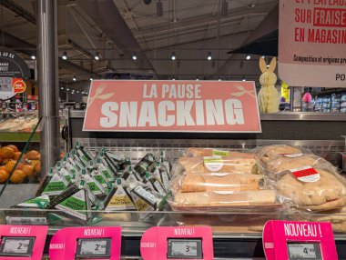 Fransa, 20 Nisan 2025: Süpermarket aperatifleri bölümü pembe tabela altında onigiri paketliyor