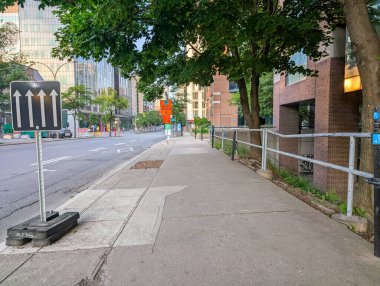 Quebec, Kanada, 05 Temmuz 2025: Ağaçlı kaldırım, tali yol işaretleri, trafik okları, modern binalar.