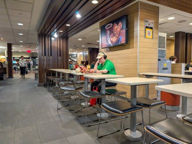 Quebec, Kanada, 07 Temmuz 2025: Kulaklık takan adam fast food restoranında tek başına oturuyor