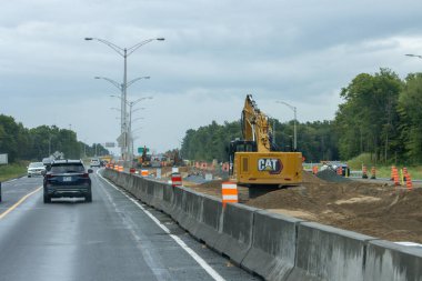 Quebec, Kanada, 20 Temmuz 2025: Yağmurlu gün trafiği ağır ekipmanlarla karayolu şantiyesinden geçti.