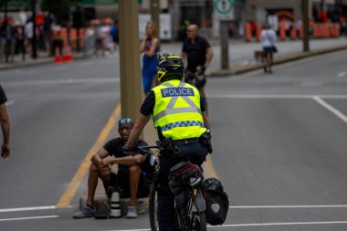 Quebec, Kanada, 05 Temmuz 2025: Şehir merkezinde oturan kişiyle Bisiklet Görüşmeleri yapan Polis Memuru