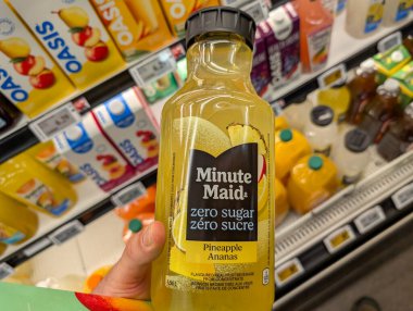 Kanada, 05 Temmuz 2025: Marketin içecek reyonunda ananas suyu şişesiyle el ele tutuşmak
