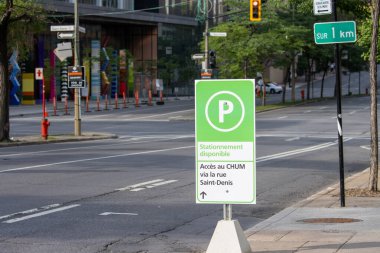 Kanada, 05 Temmuz 2025: Sessiz şehir caddesinde ağaçlar ve trafik ışıklarıyla park tabelası