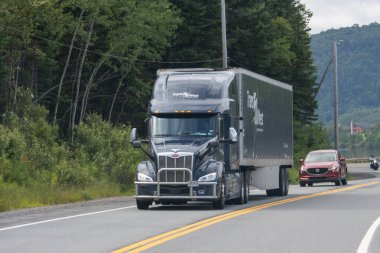 Kanada, 20 Temmuz 2025: Ağaçlarla çevrili kırsal yolda giden büyük siyah kamyonet