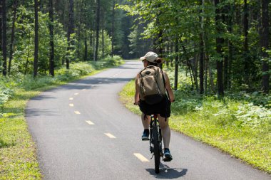 Quebec, Kanada, 15 Temmuz 2025: Ağaçların arasından parlayan güneş ışığıyla orman bisikleti patikasındaki macera